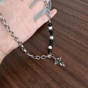 Close-up of gothic cross pendant with black and white beads on a silver Cuban chain