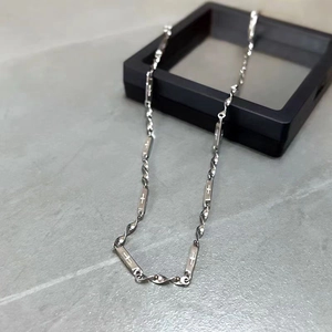 Dettaglio macro della collana Mobius in acciaio argento con incisione a croce sulle maglie