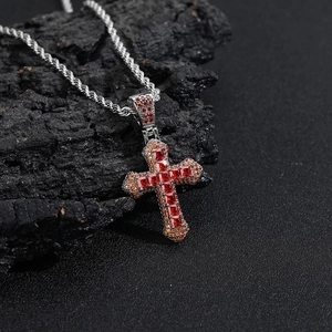 Macro detail of silver cross pendant with colorful zircon stones on a dark rock background