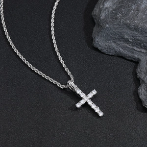 Détail macro du pendentif croix en argent avec zircons sur un fond de pierre rustique