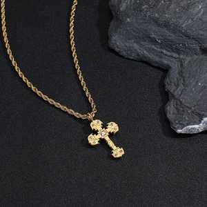 Gros plan du pendentif croix gothique dorée avec zircons sur une chaîne de corde fine