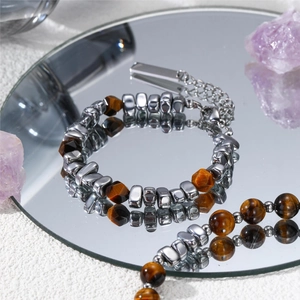 Macro detail of Tiger Eye beads and silver beads necklace on a reflective mirror surface