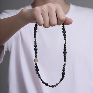 Détail macro du collier de perles noires avec cube central doré et accents en or 18 carats