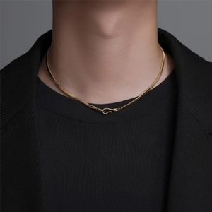 Detail of gold snake bone chain with S-shaped buckle on model neck and black jacket
