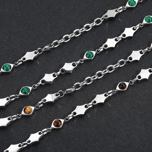 Macro detail of stainless steel rhombus chain with malachite and tiger eye stones