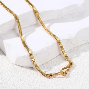 Polished gold snake chain necklace with S-hook clasp on minimalist rock display
