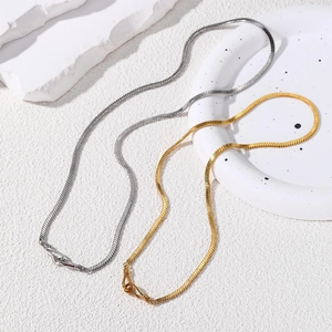 Detailed macro view of gold and silver flat snake chains on a ceramic tray display