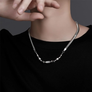 Detail of silver snake chain necklace featuring white pearls and a crystal rectangle pendant
