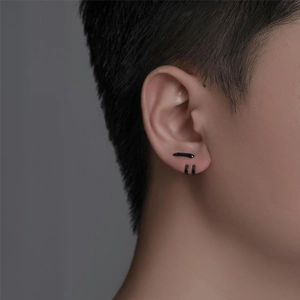 Close-up of minimalist black titanium stud earrings set on ear for men with sleek metallic finish