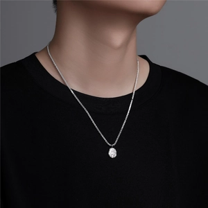 Detail of silver hammered oval pendant necklace on black shirt with metallic texture