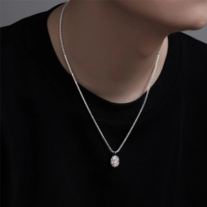 Detailed view of silver organic geometric pendant on fine chain over a black t-shirt