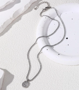 Detailed macro view of silver geometric pendant necklace on minimalist textured background