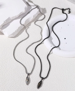 Détail de colliers de couple avec pendentifs feuilles gravés soleil et lune en argent et noir