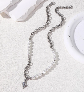 Dettaglio ravvicinato di una collana in titanio con perle e ciondolo a stella con zircone