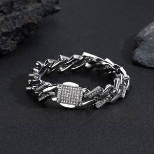 Gros plan du bracelet à maillons cubains argentés serti de strass sur fond de pierre noire