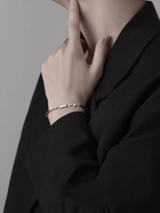 Gros plan du bracelet Mobius en acier titane argenté porté sur un costume noir