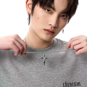 Ensemble collier pendentif croix et boucles d'oreilles étoile porté par un mannequin chic