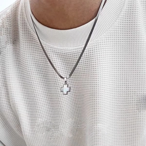 Silver snake chain necklace with white clover cross shell pendant on waffle sweater