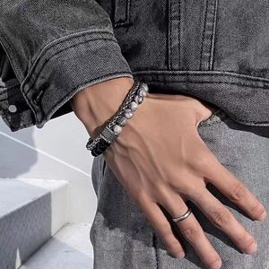 Détail d'un bracelet double couche en titane avec pierres œil de tigre et chaîne en métal au poignet