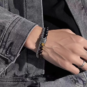 Détail de bracelet en œil de tigre et acier inoxydable porté avec une bague argentée