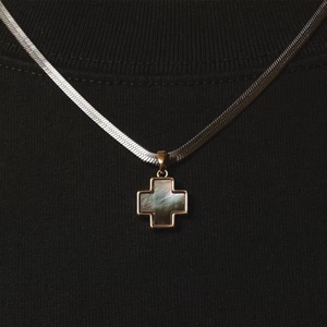 Detail of cross pendant with dark mother of pearl inlay on black knit sweater