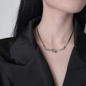 Polished silver knot pendant necklace with flat snake chain worn on a black suit jacket