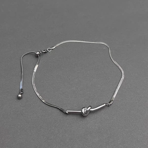 Detail of silver snake chain knot necklace with adjustable sliding clasp mechanism