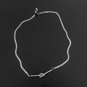 Close-up of minimalist silver snake chain with knot charm and adjustable draw bead