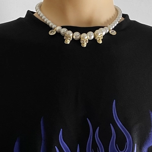 Detail of hip hop pearl necklace with gold skulls and diamonds worn on a neck