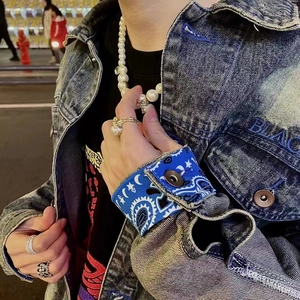 Close-up of pearl skull necklace and paisley pattern denim jacket in street fashion style