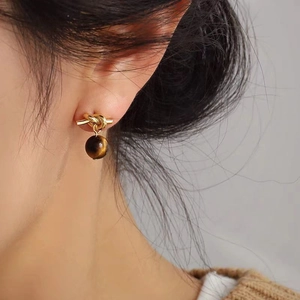 Detail of tiger eye stone knot earring worn by model showing vintage metallic texture