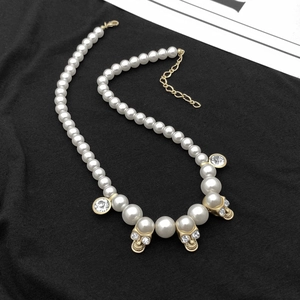 Detail of hip hop pearl necklace featuring crystal skull charms and golden adjust chain