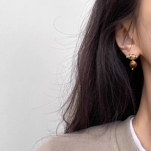 Detailed view of Maillard style tiger eye stone knot earrings worn by a model