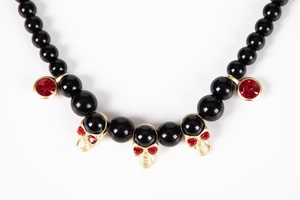 Macro detail of gothic beaded necklace with gold skull pendants and red rhinestones