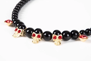 Macro shot of hip hop necklace with black beads, gold skulls and red heart pendants