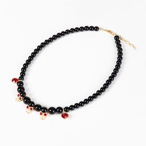 Gothic beaded necklace with gold skull pendants and red rhinestones on white background