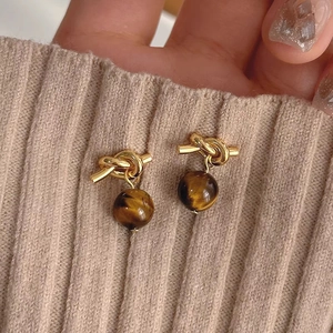 Detailed shot of golden knot earrings featuring brown tiger eye stone beads for women