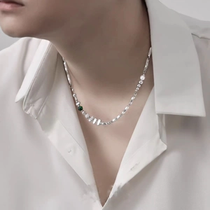 Detail of silver Mobius necklace with green gemstone, pearl, and steel beads on model