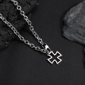 Vue macro du pendentif croix évidée avec gemmes rouges sur chaîne à maillons argent