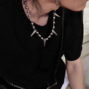 Detail of punk style ball chain necklace featuring five metallic silver cone spikes