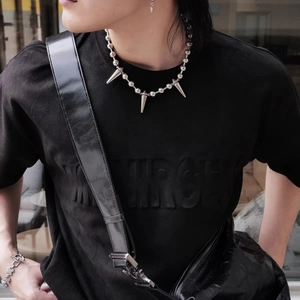 Detailed view of silver bead chain necklace with sharp cone spikes on model outfit
