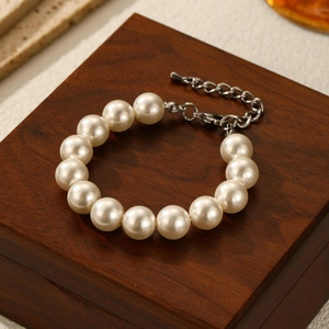 Close-up of white round pearl necklace with silver clasp on a wooden jewelry box