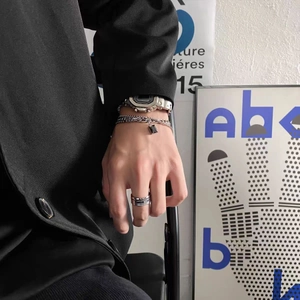 Gros plan sur une montre en métal argenté et un bracelet à pendentif noir pour homme