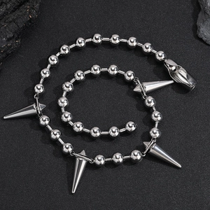 Silver bead chain necklace with punk cone spikes on a textured black background