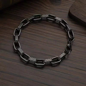 Detail of vintage gunmetal chain bracelet with twill engraving on dark wood background