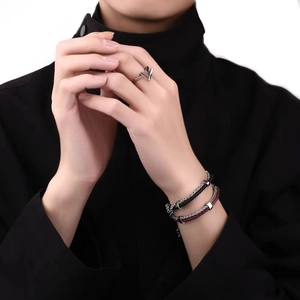 Detail of silver V-shaped ring and woven leather bracelets on a model's wrist