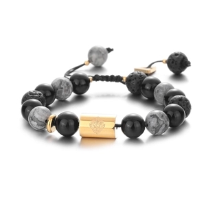 Detail of beaded bracelet with black lava rock and a golden lion head metallic cylinder