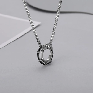 Détail macro du pendentif double boucle en bambou noir et argent sur une chaîne box