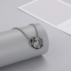 Gros plan sur deux anneaux en argent texture bambou avec émail noir et chaîne vénitienne