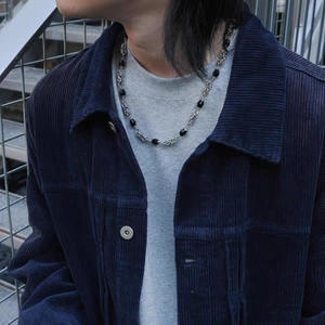 Detail of hip hop cuban chain necklace with black beads on model in corduroy jacket